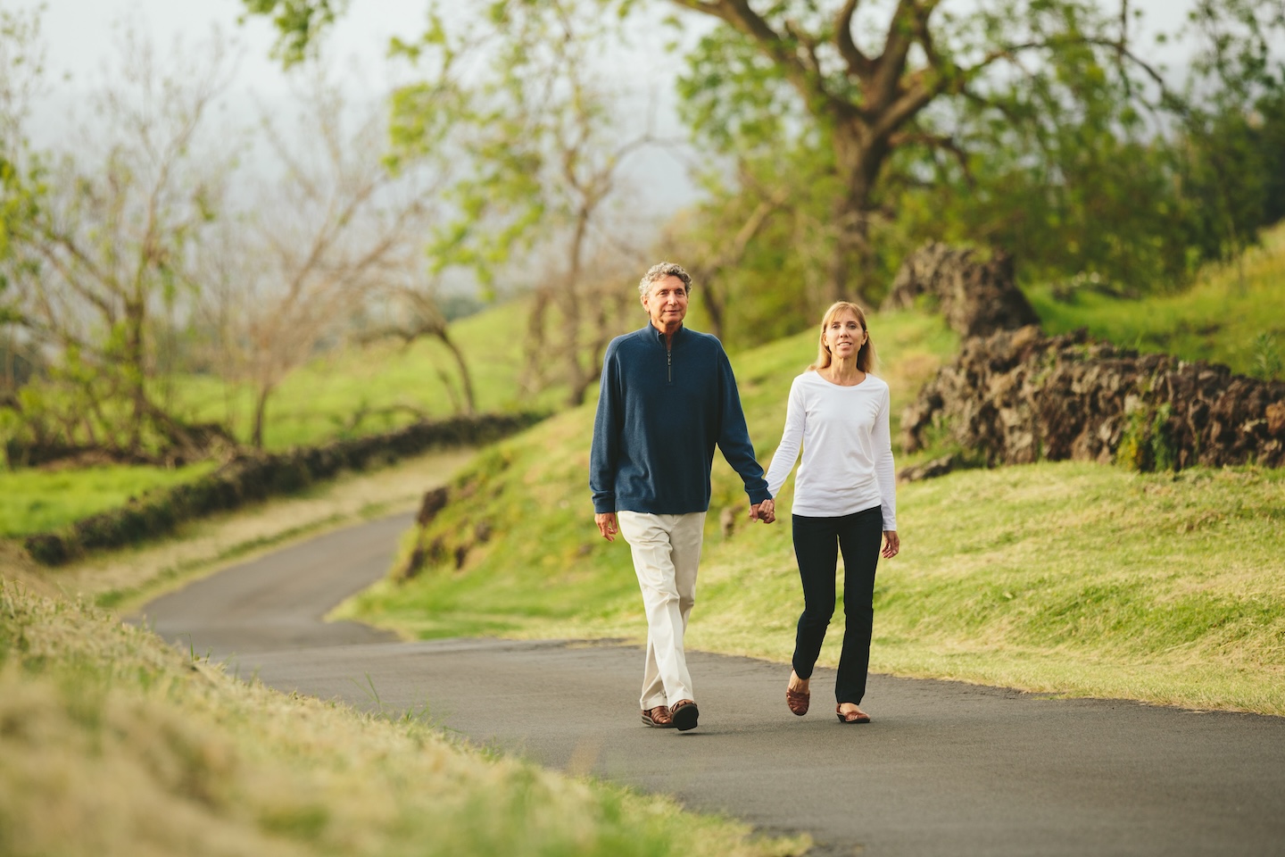 Happy loving middle aged couple walking on beautiful country road